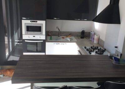 Réalisation IN’D&CO: Cuisine avec ilot central; gris anthracite et blanche laquée. Plan de travail effet bois gris en deux nuances de couleurs. Réalisation à Châteauneuf les Martigues en 2016