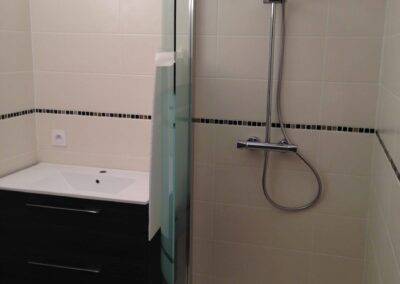 Réalisation INDECO CARRELAGE salle de bain avec douche, carrelage sol noir, carrelage mur beige. Meuble de salle de bain noir