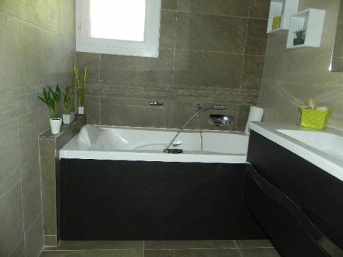 Réalisation INDECO CARRELAGE salle de bain baignoire, avec meuble effet bois wengé. Carrelage beige